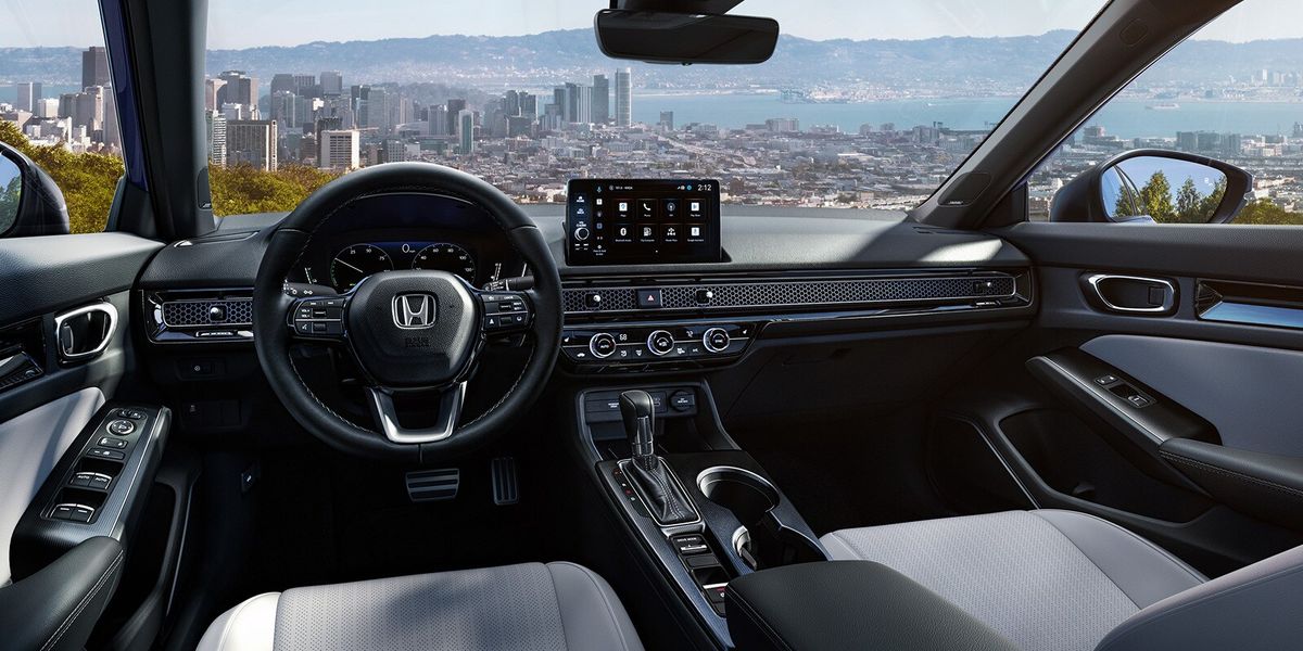 2026 Honda Civic Sedan Sport Touring Hybrid dashboard and front cabin view overlooking a city skyline (Compact Sedan)