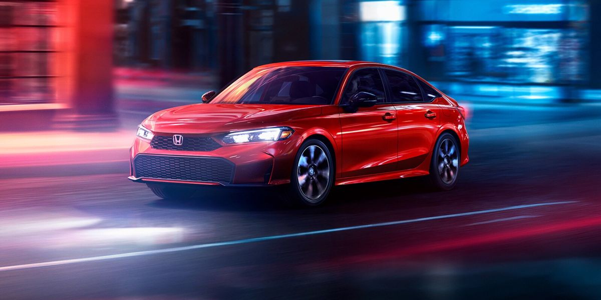 2026 Honda Civic Sedan Sport Touring Hybrid in Rallye Red front three-quarter view driving through a city (Compact Sedan)